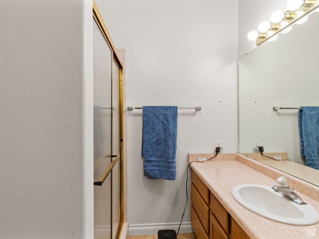 Full bathroom with baseboards, a shower with shower door, and vanity