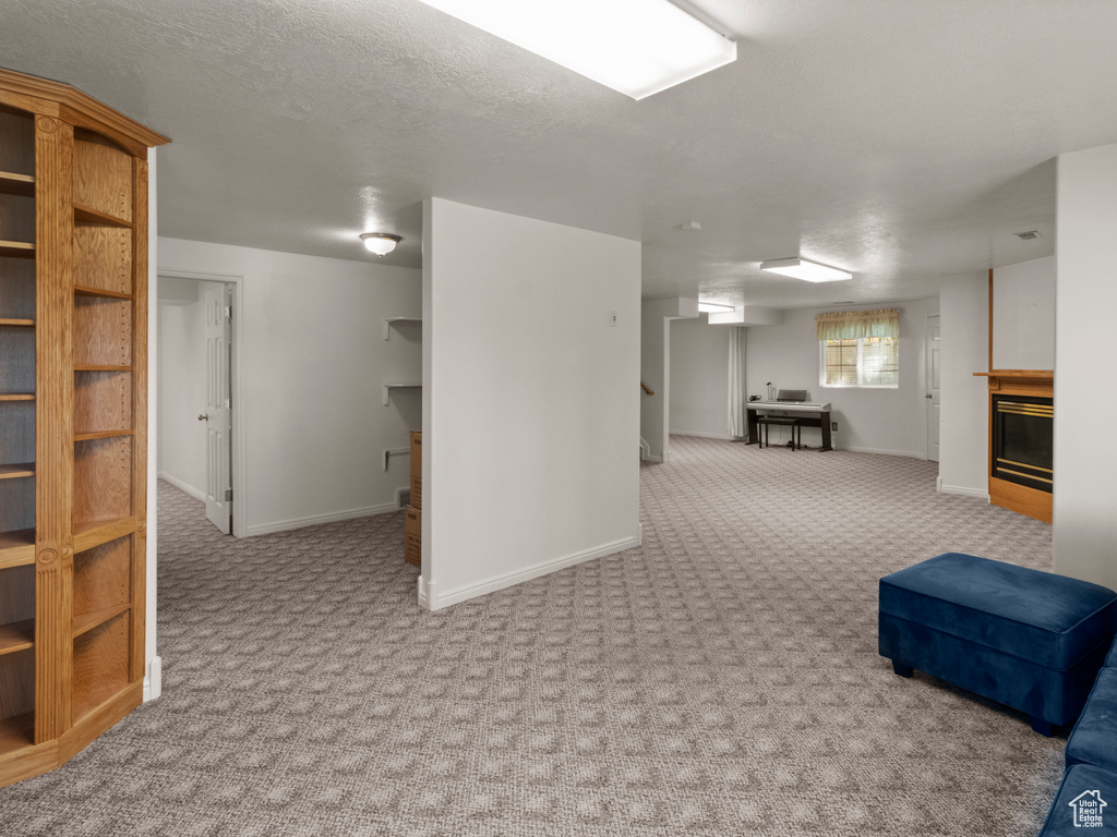 Below grade area featuring carpet flooring, baseboards, and a glass covered fireplace