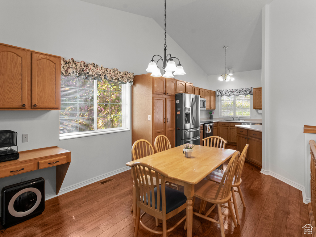 Dining area featuring a notable chandelier, high vaulted ceiling, baseboards, dark wood-type flooring, and visible vents