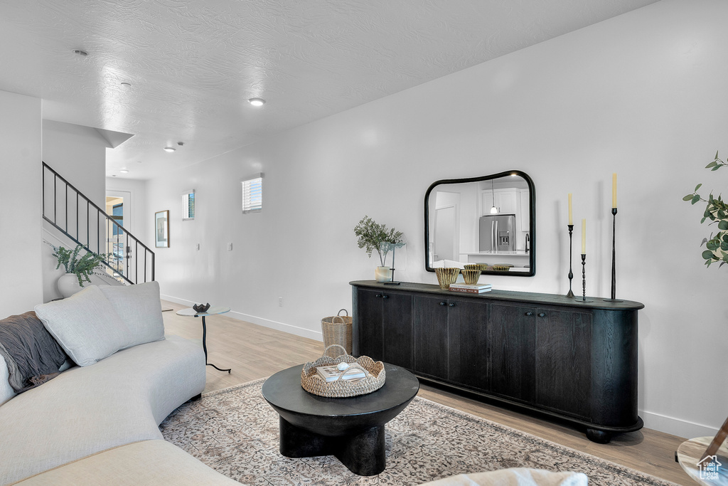 Living room with stairs, baseboards, and light wood-style flooring