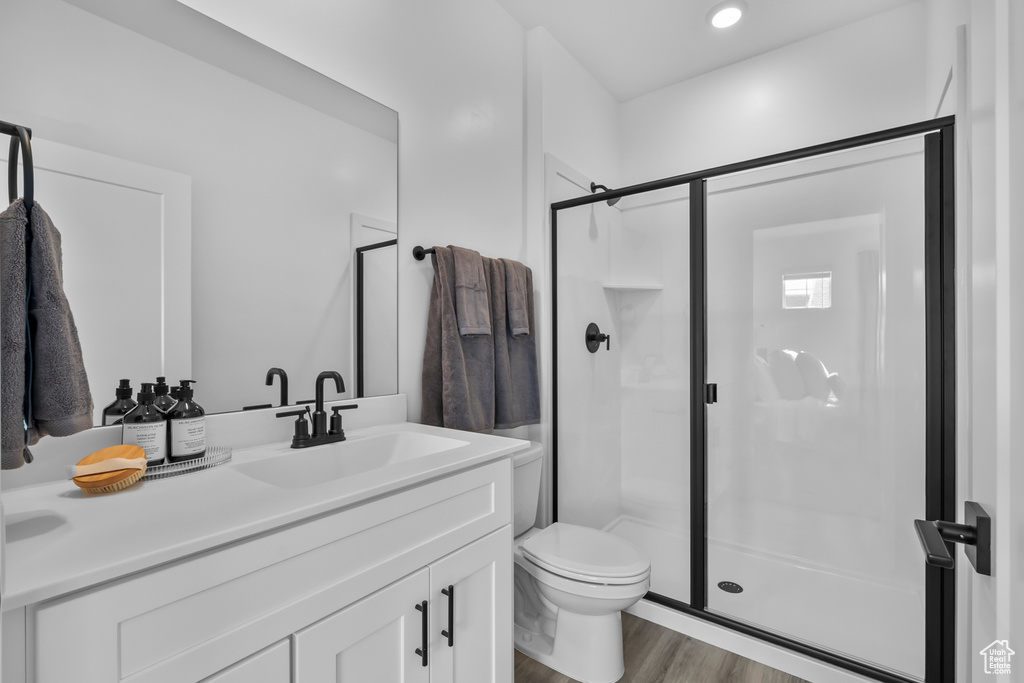 Full bath featuring vanity, wood finished floors, toilet, and a shower stall