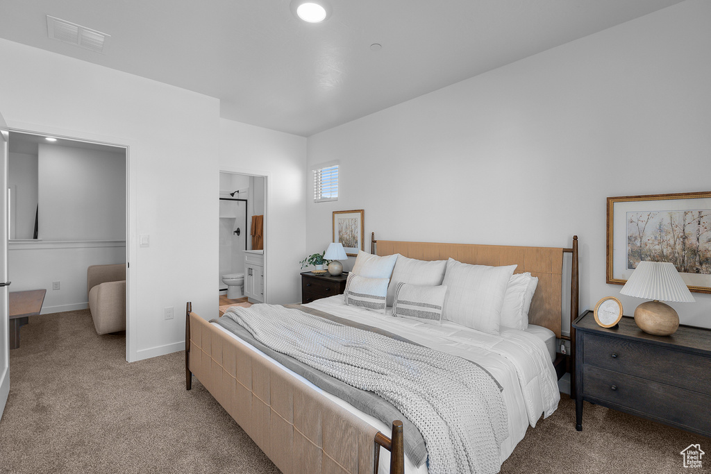 Bedroom with connected bathroom, baseboards, visible vents, and light carpet