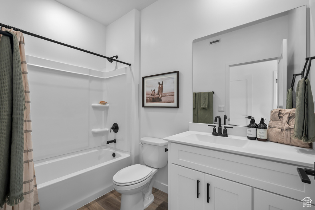 Bathroom featuring vanity, toilet, shower / bathtub combination with curtain, baseboards, and wood finished floors