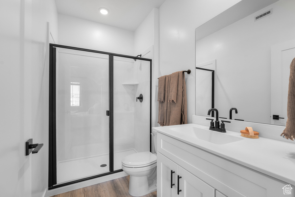 Full bathroom with visible vents, a stall shower, wood finished floors, vanity, and toilet