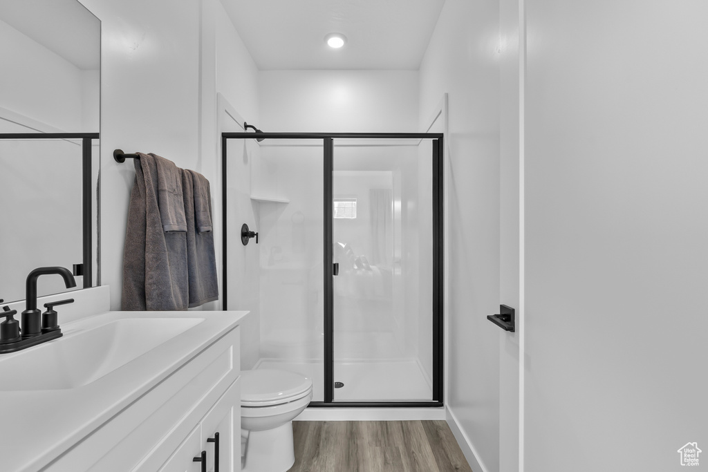 Bathroom with a shower stall, toilet, and wood finished floors
