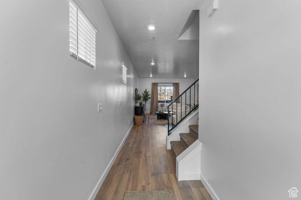 Hall with baseboards, wood finished floors, and stairway