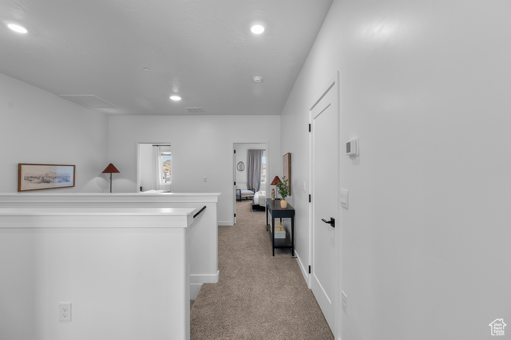 Corridor featuring baseboards, visible vents, recessed lighting, and light colored carpet