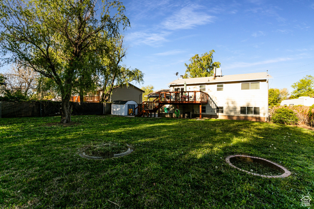 View of yard with fence, a storage unit, a wooden deck, stairway, and an outdoor structure