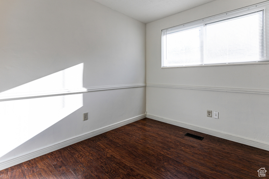 Spare room featuring visible vents, baseboards, and wood finished floors