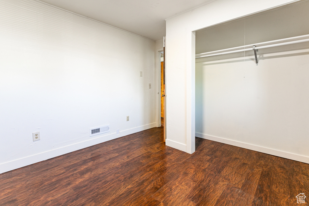 Unfurnished bedroom with baseboards, visible vents, wood finished floors, and a closet