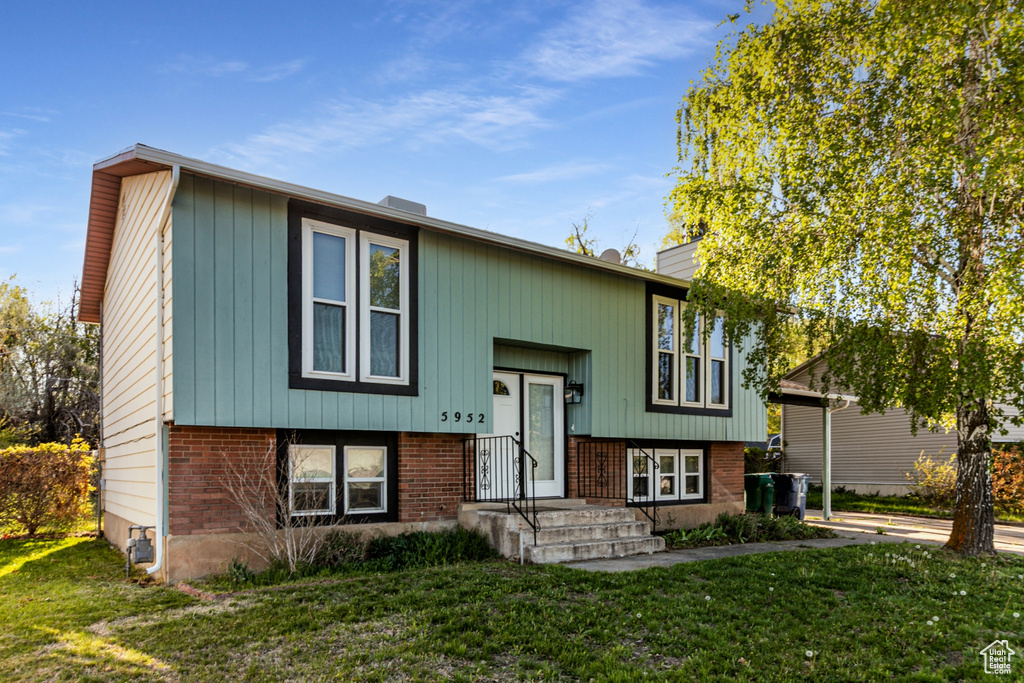 Split foyer home with brick siding and a front yard