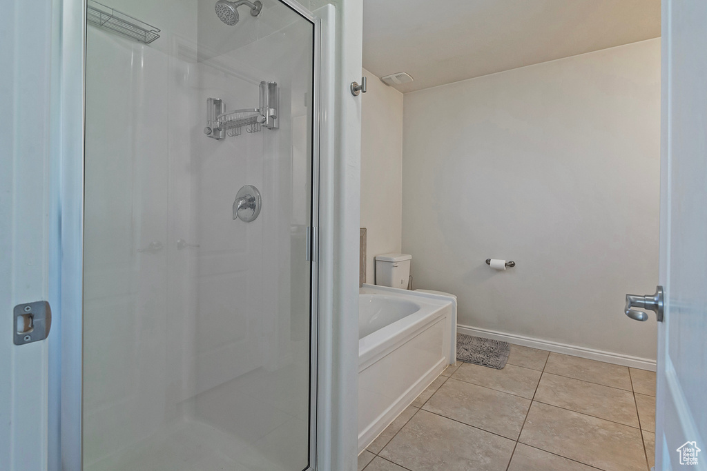 Bathroom featuring baseboards, tile patterned flooring, a stall shower, and a bath