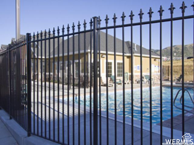 View of gate with fence and a community pool