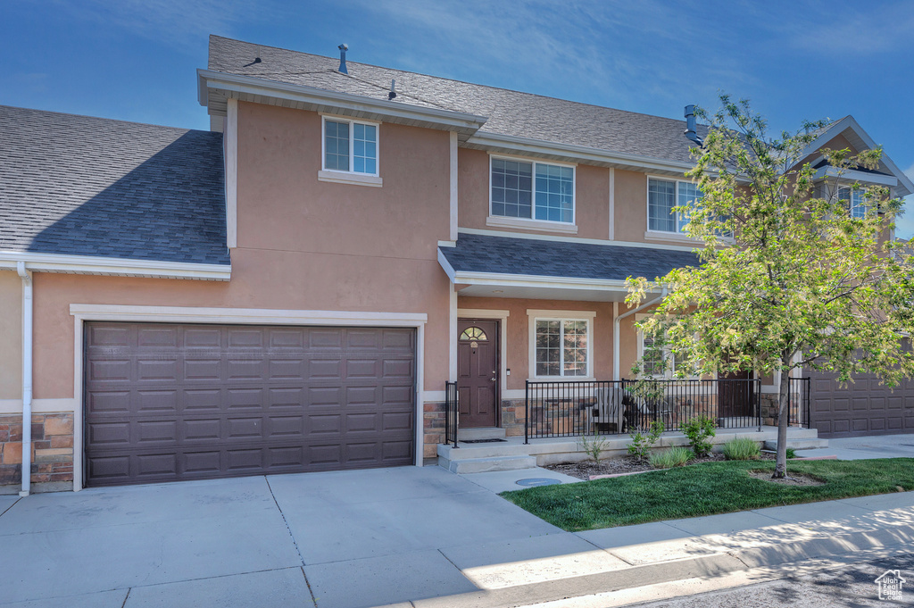 View of front of house with covered porch, driveway, a garage, a shingled roof, and stucco siding