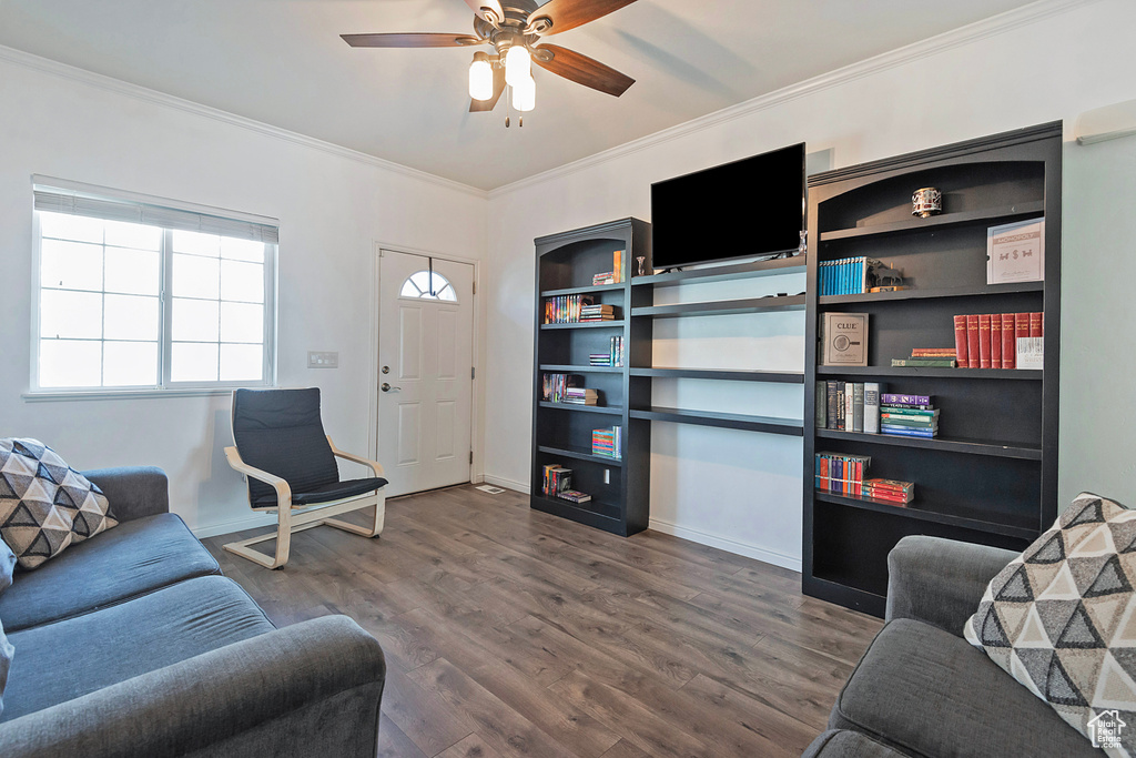 Living room with crown molding, baseboards, ceiling fan, and wood finished floors