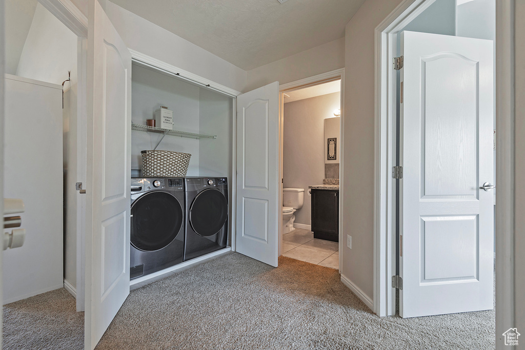 Clothes washing area featuring carpet floors, baseboards, laundry area, and washing machine and clothes dryer