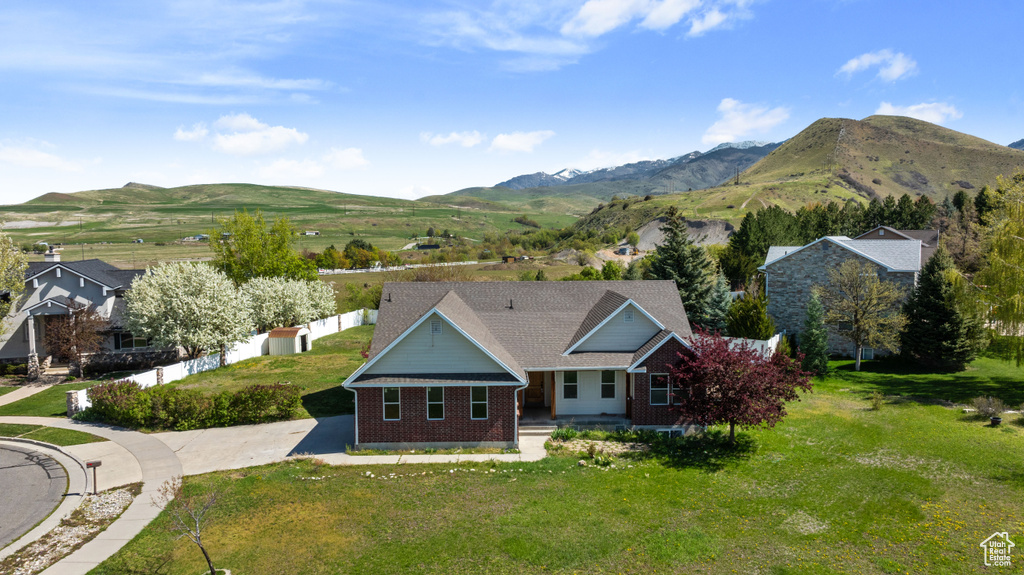 Exterior space featuring brick siding, a front lawn, a mountain view, and concrete driveway