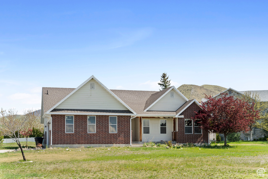 View of front of house with covered porch, brick siding, a mountain view, and roof with shingles