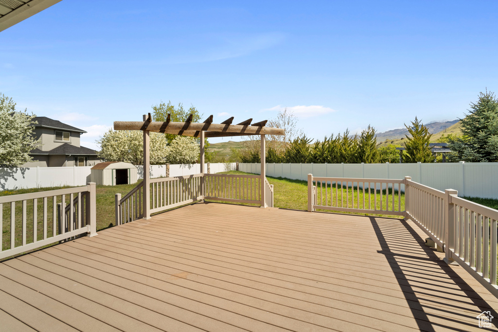 Deck with a fenced backyard, an outbuilding, a yard, and a shed