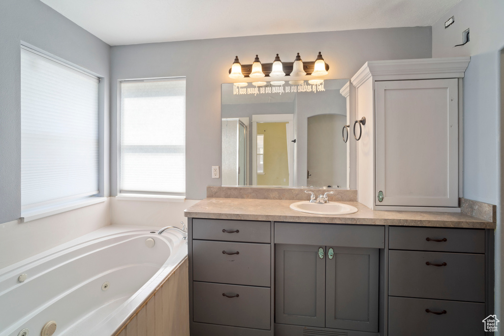 Full bathroom featuring a tub with jets, plenty of natural light, and vanity