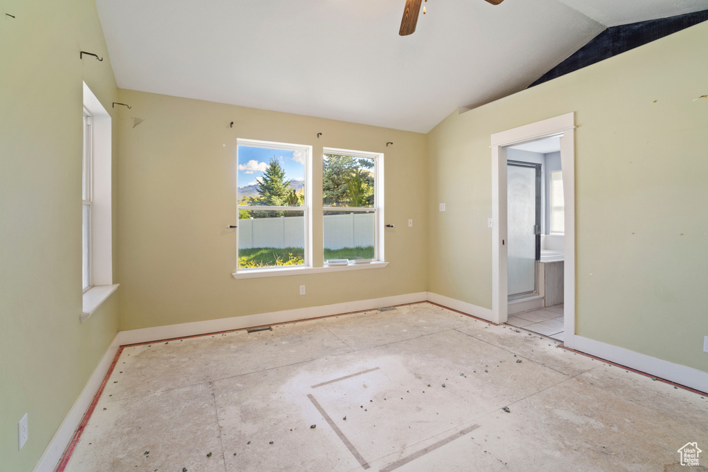 Empty room with a ceiling fan, baseboards, and lofted ceiling