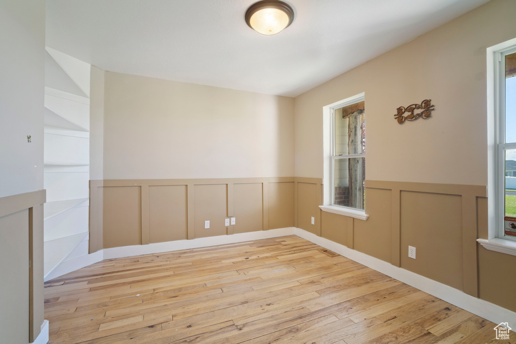 Unfurnished room with a wainscoted wall, hardwood / wood-style floors, and a wealth of natural light