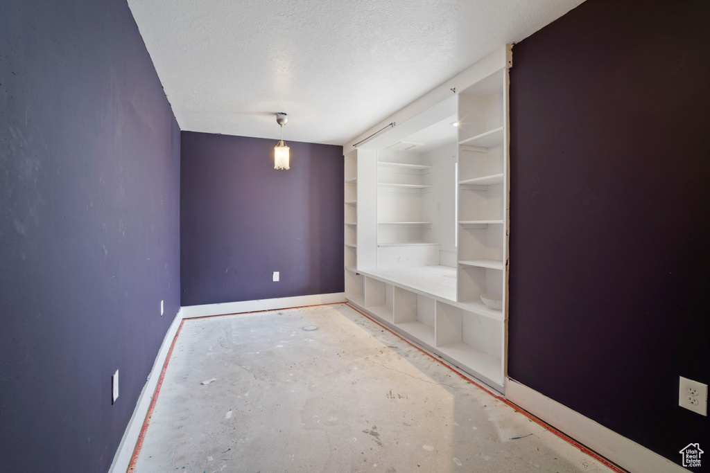 Empty room with a textured ceiling and baseboards