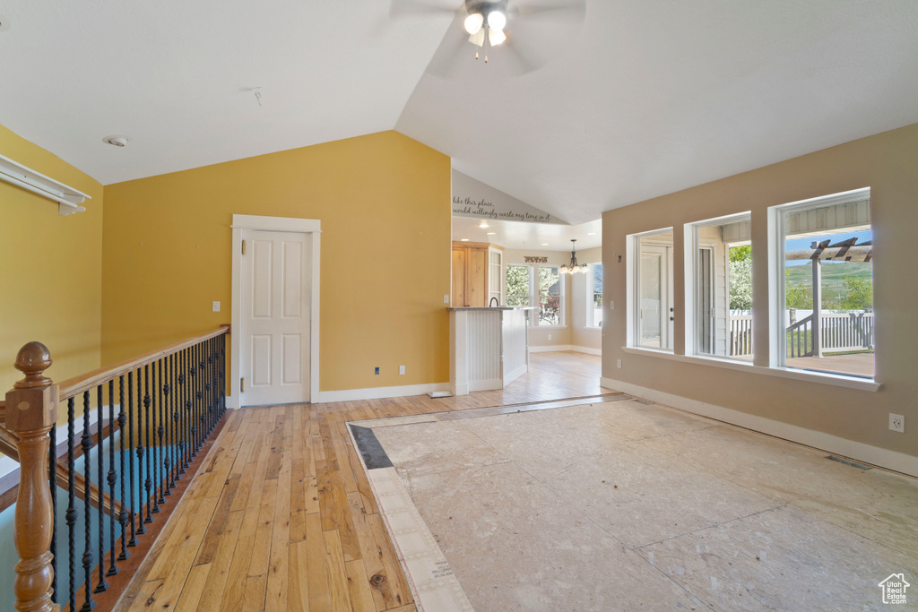 Interior space with visible vents, baseboards, light wood-type flooring, ceiling fan with notable chandelier, and vaulted ceiling