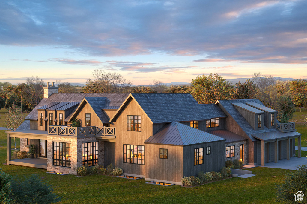 Rear view of property with a balcony, a yard, metal roof, and a standing seam roof