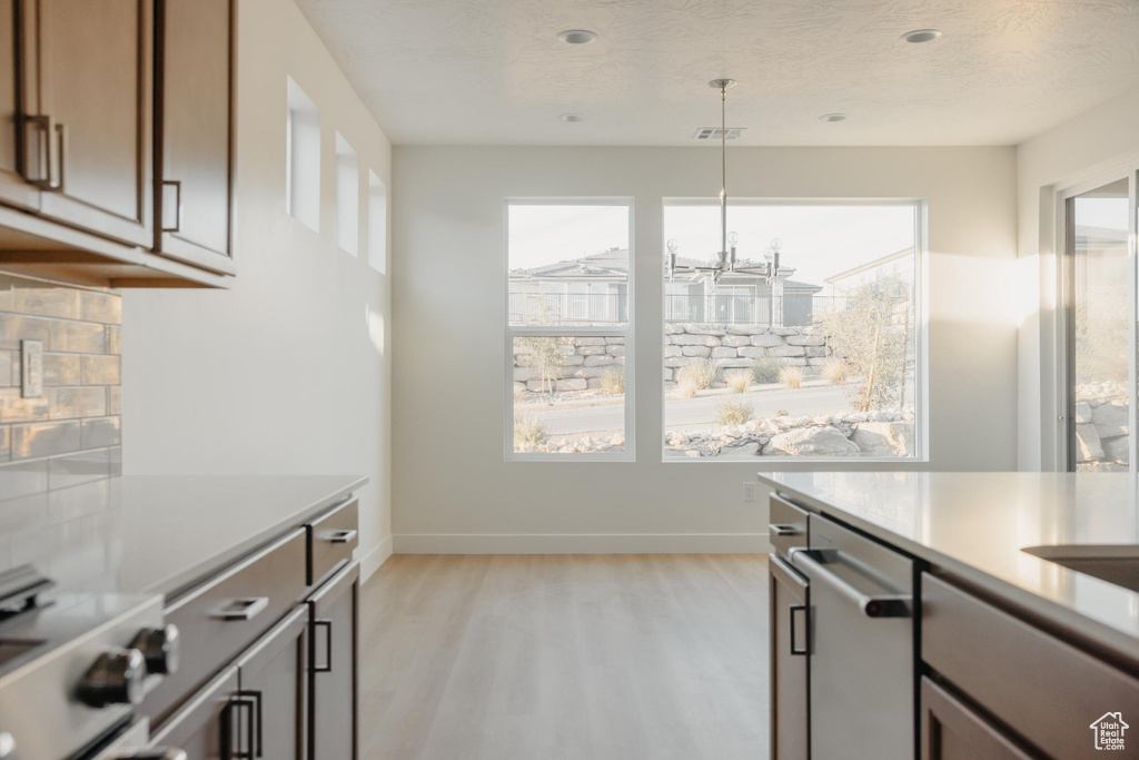 Kitchen with decorative light fixtures, stove, light countertops, baseboards, and light wood finished floors