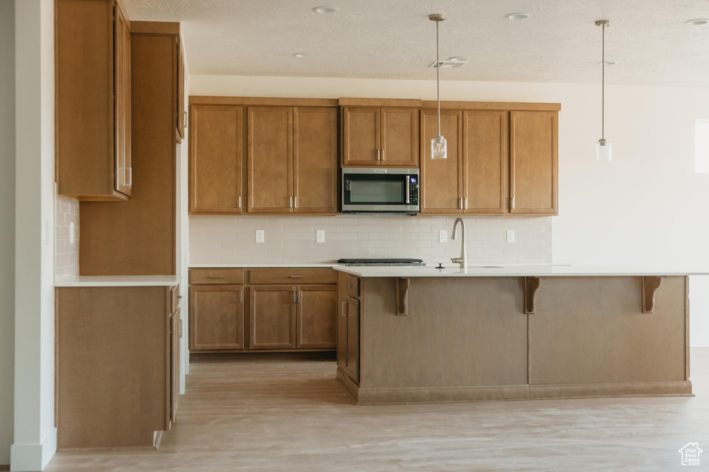 Kitchen featuring a sink, stainless steel microwave, and brown cabinets
