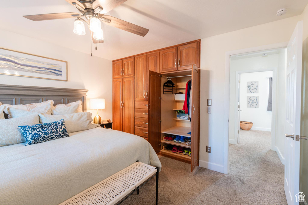 Bedroom with baseboards, ceiling fan, light carpet, and a closet
