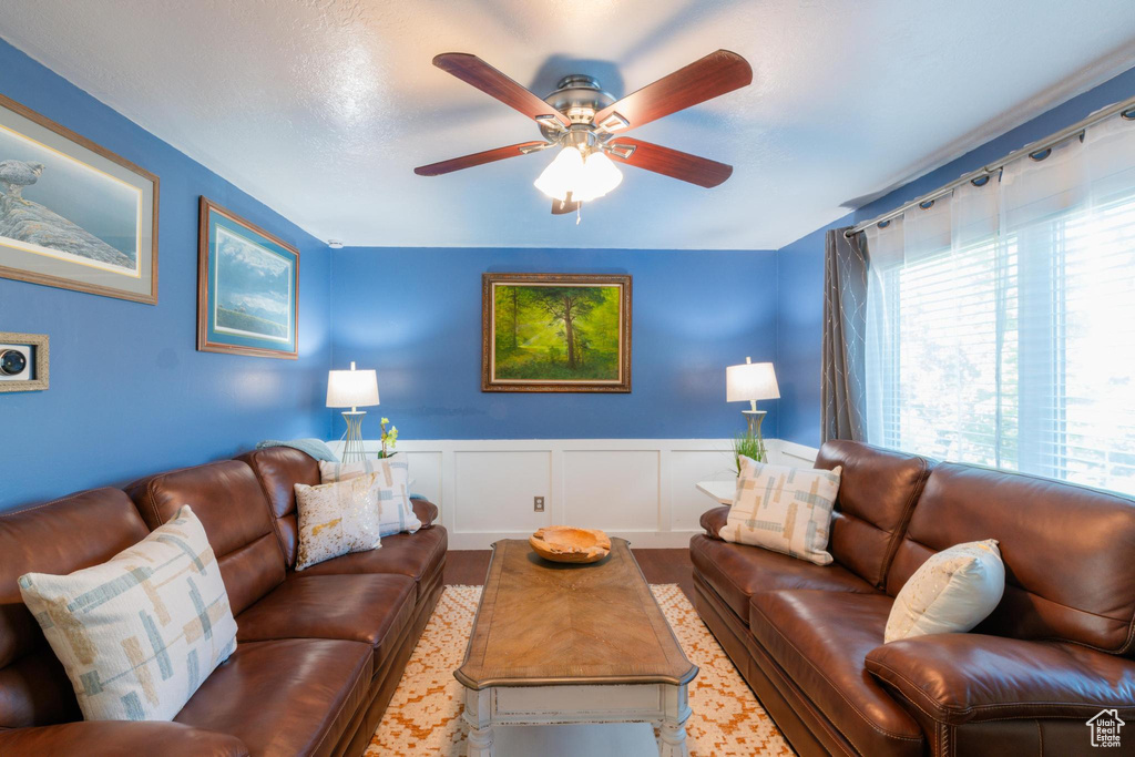 Living area featuring wainscoting and ceiling fan