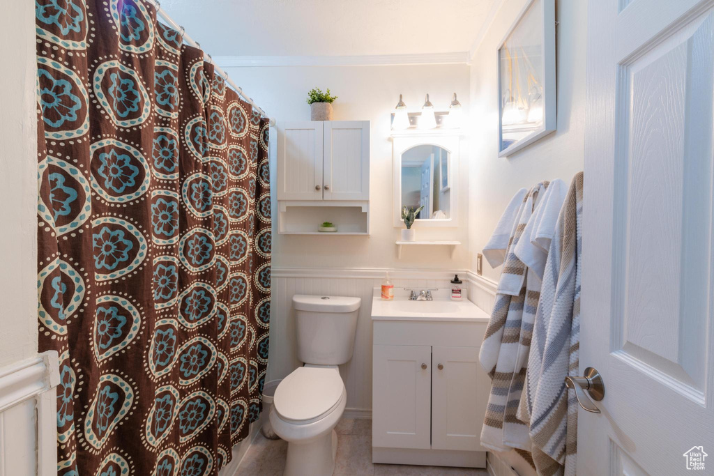 Full bathroom with vanity, wainscoting, curtained shower, and toilet