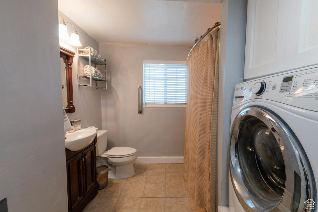 Full bath featuring vanity, stacked washer / dryer, toilet, baseboards, and a shower with curtain