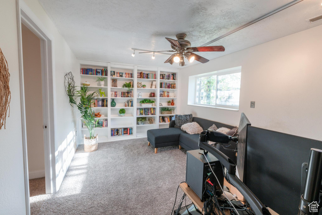 Living area featuring a ceiling fan, visible vents, built in shelves, and carpet