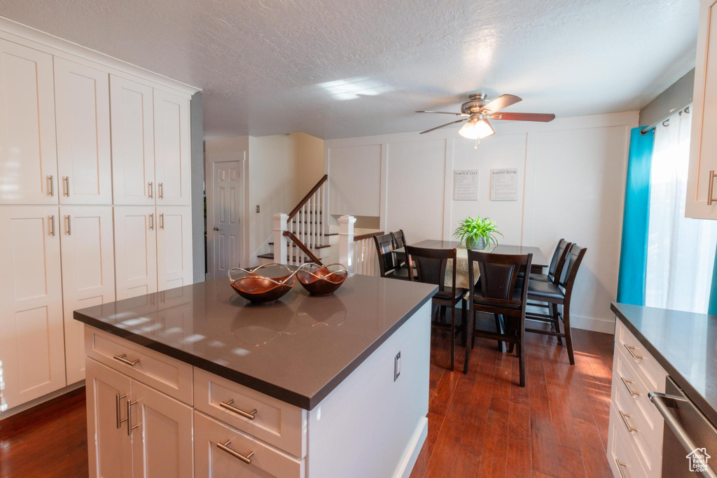 Kitchen featuring dark wood finished floors, ceiling fan, a kitchen island, and dark countertops