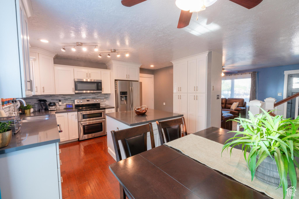 Kitchen with ceiling fan, dark countertops, appliances with stainless steel finishes, tasteful backsplash, and white cabinets