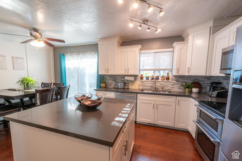 Kitchen with a sink, dark countertops, decorative backsplash, and appliances with stainless steel finishes
