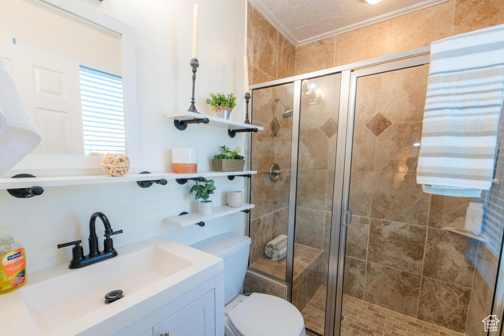 Bathroom with toilet, a shower stall, ornamental molding, and vanity