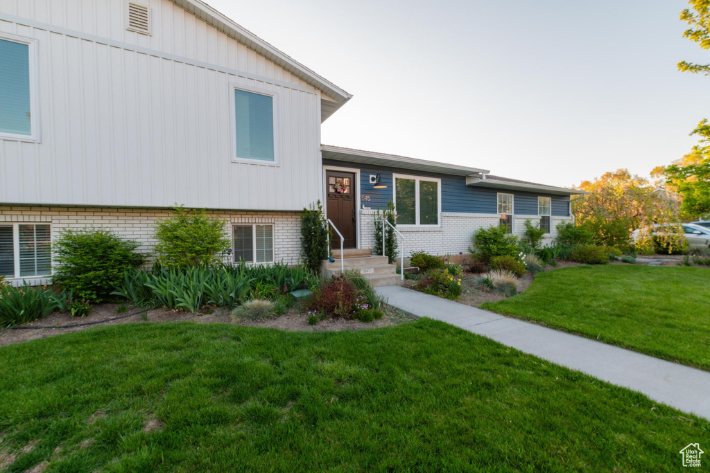 Tri-level home featuring brick siding, board and batten siding, and a front yard