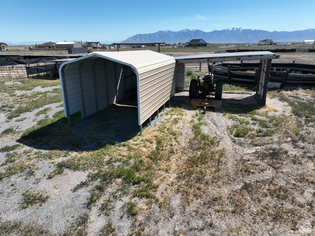 View of outbuilding with fence, a mountain view, and a carport