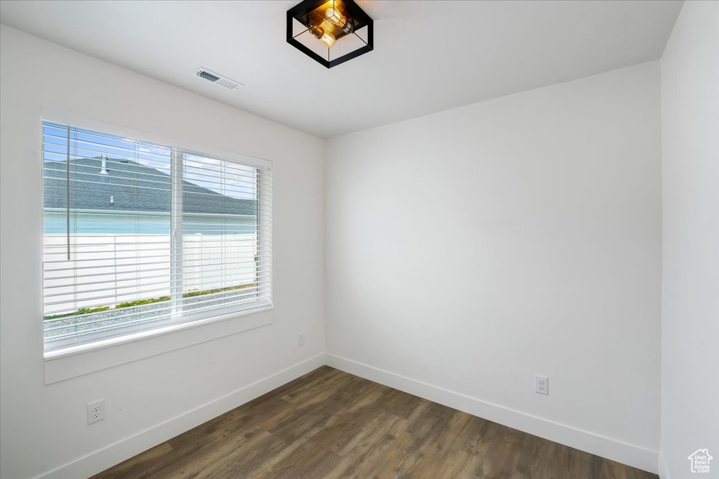 Unfurnished room with baseboards, dark wood-type flooring, and visible vents