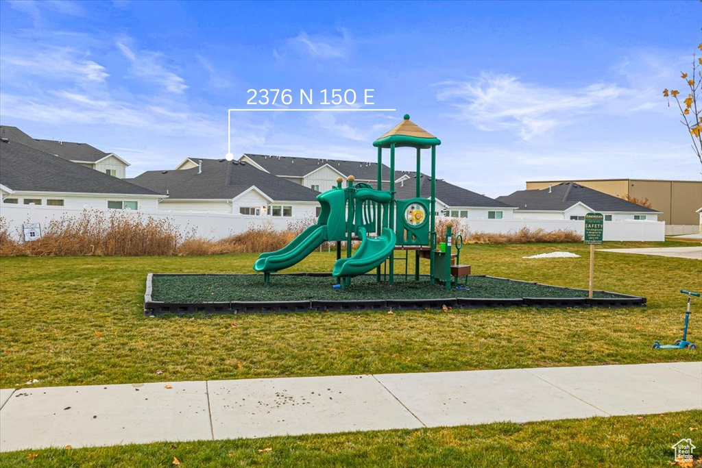Communal playground featuring a lawn, fence, and a residential view