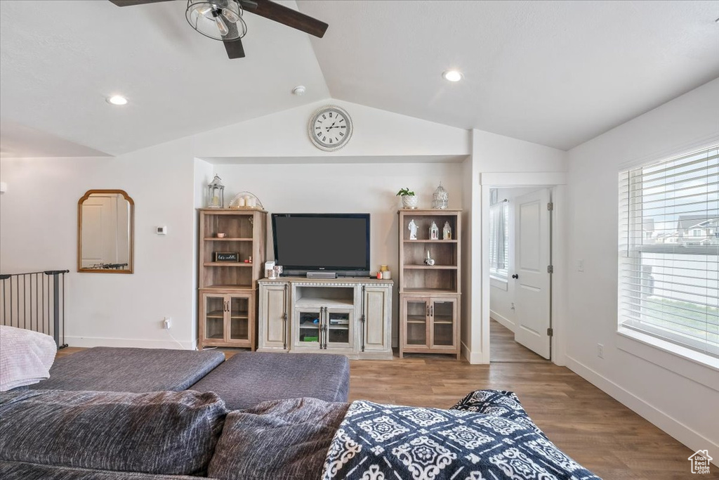 Living room with wood finished floors, lofted ceiling, baseboards, recessed lighting, and a ceiling fan