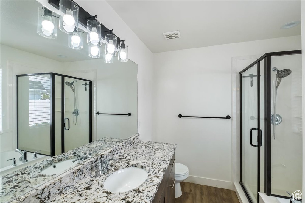Bathroom featuring vanity, a shower stall, wood finished floors, and visible vents