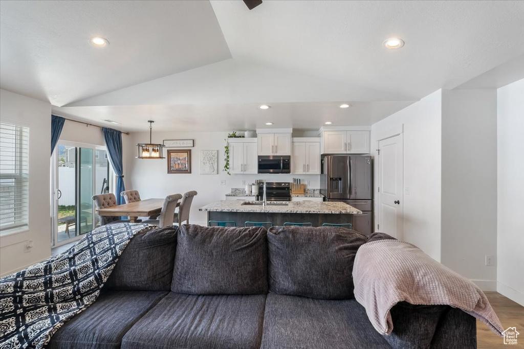 Living room with recessed lighting, baseboards, wood finished floors, and lofted ceiling