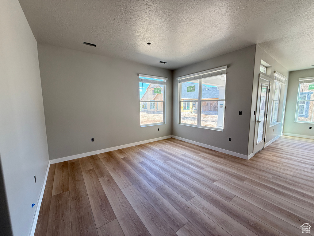 Interior space with baseboards, a textured ceiling, and light wood finished floors