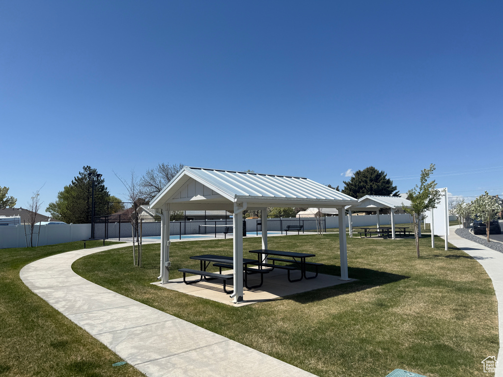 View of property\'s community with a gazebo, a swimming pool, fence, and a yard