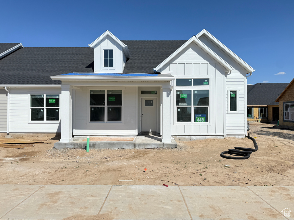 Modern farmhouse style home featuring a shingled roof, board and batten siding, and a porch